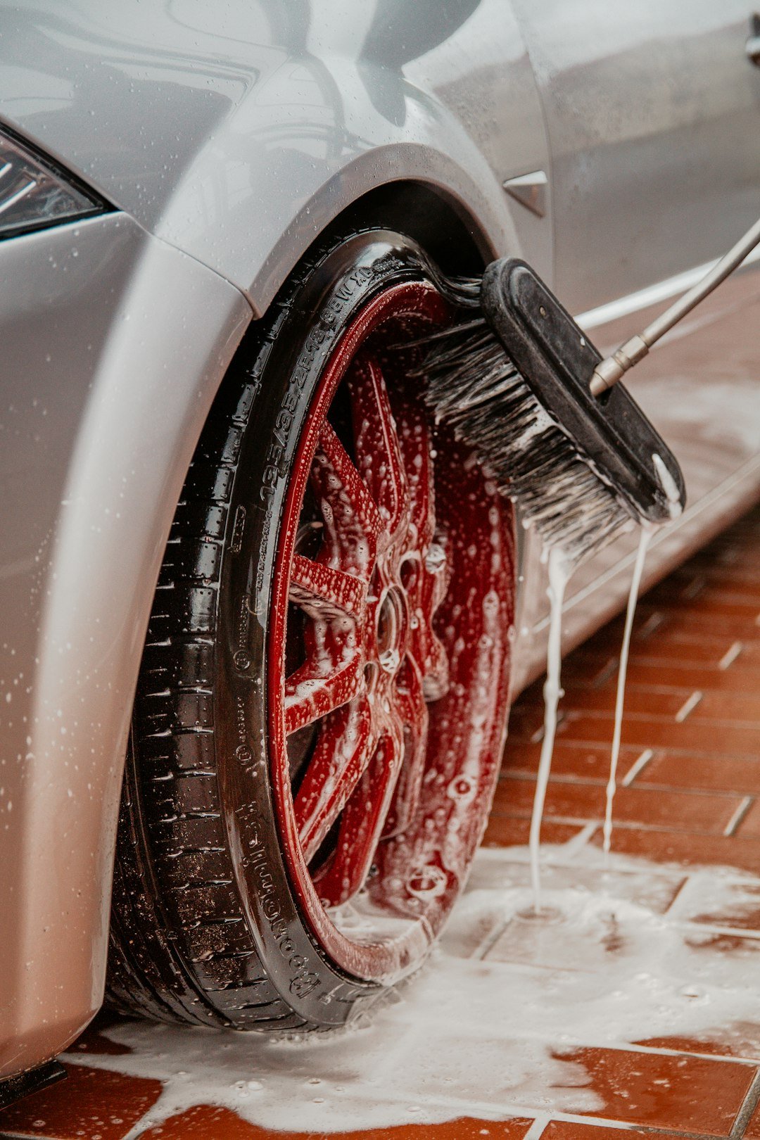 Pressure washer hose and lance cleaning a car wheel at a car wash