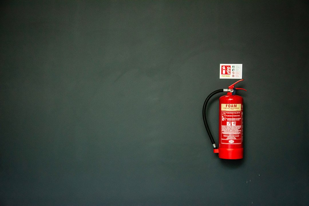 Red fire extinguisher with fire extinguisher hose mounted on an industrial wall