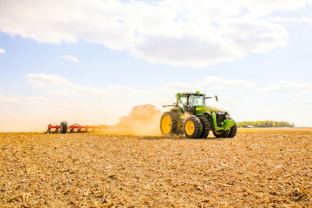 Tractor pulling a trailer across a farm field, illustrating hydraulic hoses for electric tractors and e-farm equipment in India