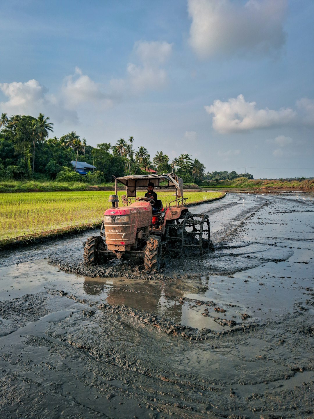 Tractor working a muddy field under monsoon clouds — monsoon hydraulic hose maintenance for farm and construction equipment